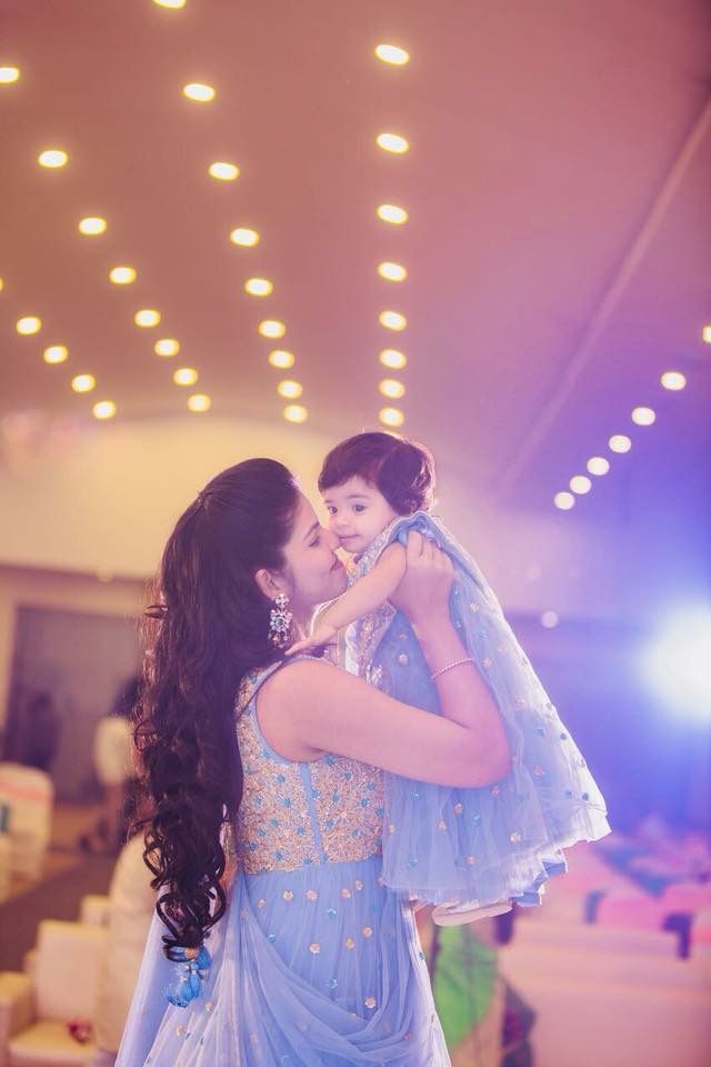 a woman holding a child in her arms while wearing a blue dress and tiara