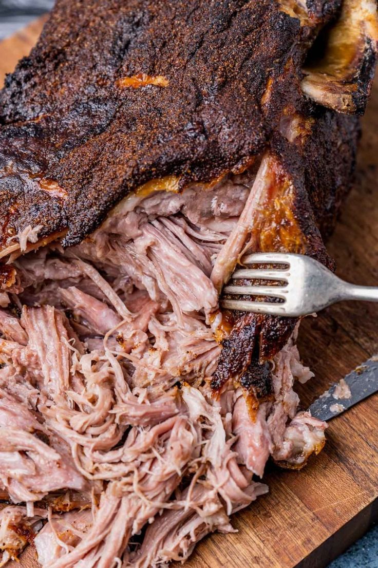 a large piece of meat on a cutting board with a knife and fork in it