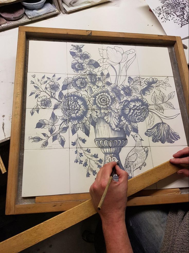 a person is drawing flowers on a piece of paper with a pencil and watercolor