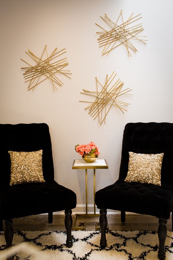 two black chairs sitting next to each other in front of a wall with gold stars on it