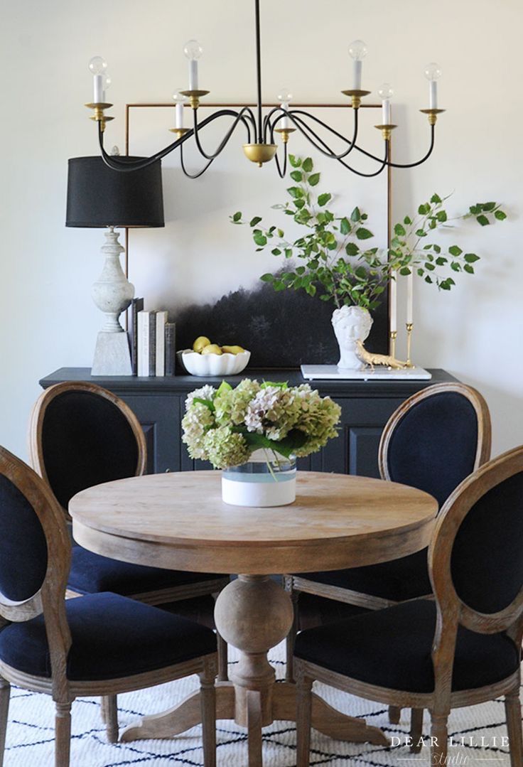 a dining room table with blue chairs and a chandelier hanging above it in the corner