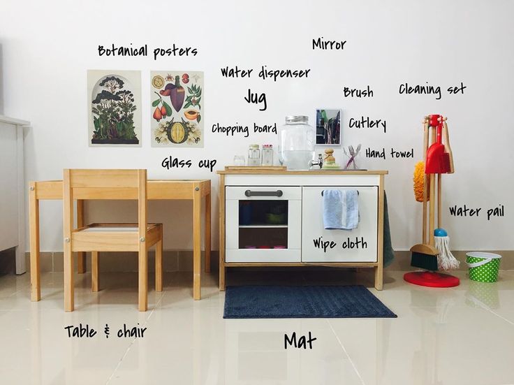 a kitchen area with white walls and wooden furniture, including an oven, table, chair, potty pan, mirror, water dispenser, etc