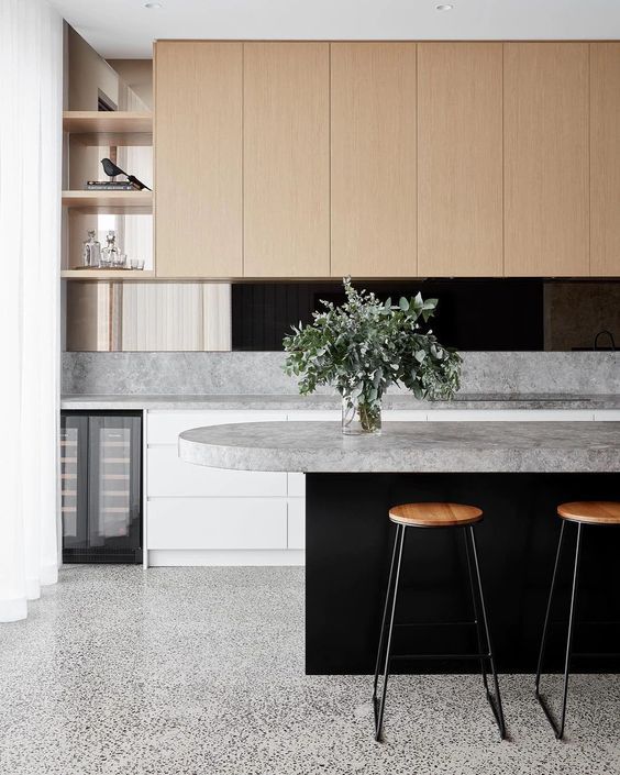 two stools are in front of an island with marble countertops and cabinets on either side