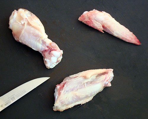 three pieces of raw meat sitting next to a knife on a black surface with one piece cut in half