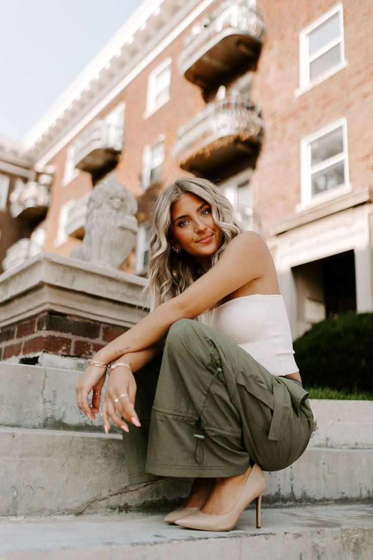 a woman is sitting on the steps in front of a building and posing for a photo