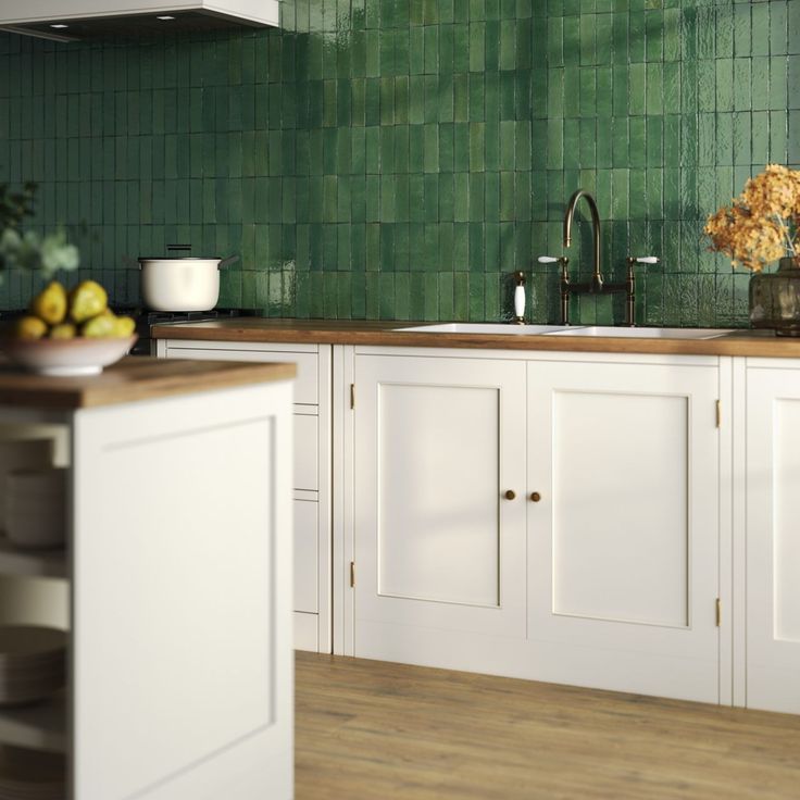 a kitchen with white cabinets and green tile backsplash