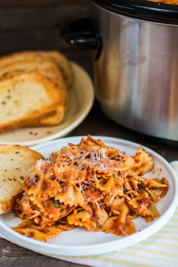 pasta and bread on a plate with a crock pot in the background