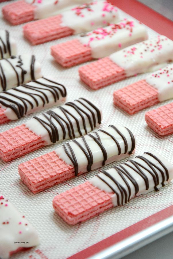 pink and white waffles are arranged on a baking sheet with chocolate drizzle