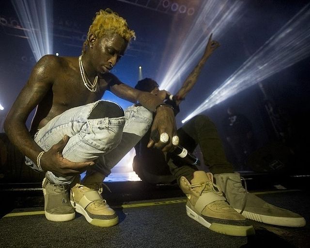 a man sitting on the ground with his feet up in front of him and lights behind him