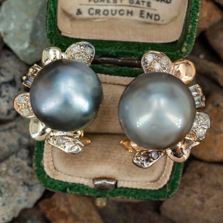 These gorgeous pearl earrings are each accented with one (1), post set, cultured Tahitian pearl, eleven (11), bead set, round brilliant cut diamonds and two (2), prong set, baguette cut diamonds. The earrings measure 22.8mm X 17.3mm. The earrings are finished with hinged omega backs for pierced ears. One of the baguette diamonds is unnoticeably chipped. Pear Diamond Earrings, Baguette Cut, Baguette Cut Diamond, Pear Diamond, Tahitian Pearls, Baguette Diamond, Round Brilliant, Round Brilliant Cut Diamond, Brilliant Cut Diamond