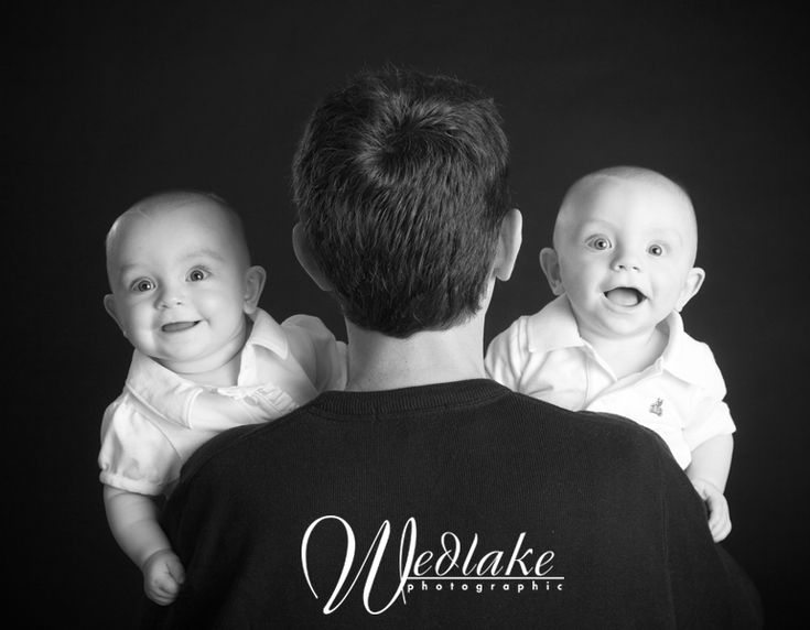 a man holding two babys in his arms and looking at the camera while wearing a t - shirt that says we wake