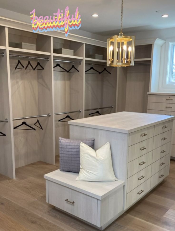 a large walk in closet with lots of drawers and pillows on the bench next to it