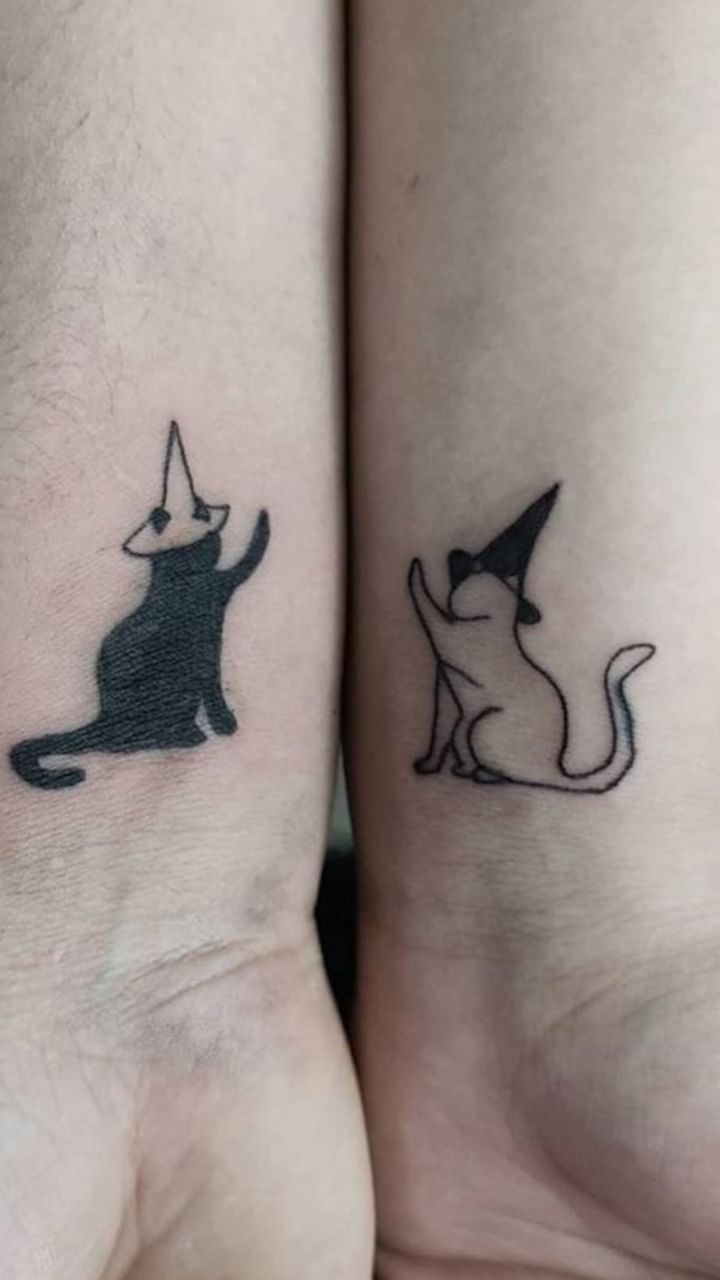 two small tattoos on the arms of people with cats and witches hats on their heads