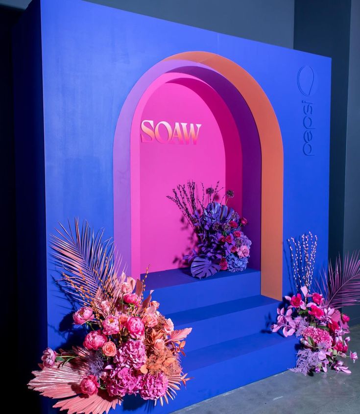 a blue and pink stage with flowers on the steps next to it that says soaw