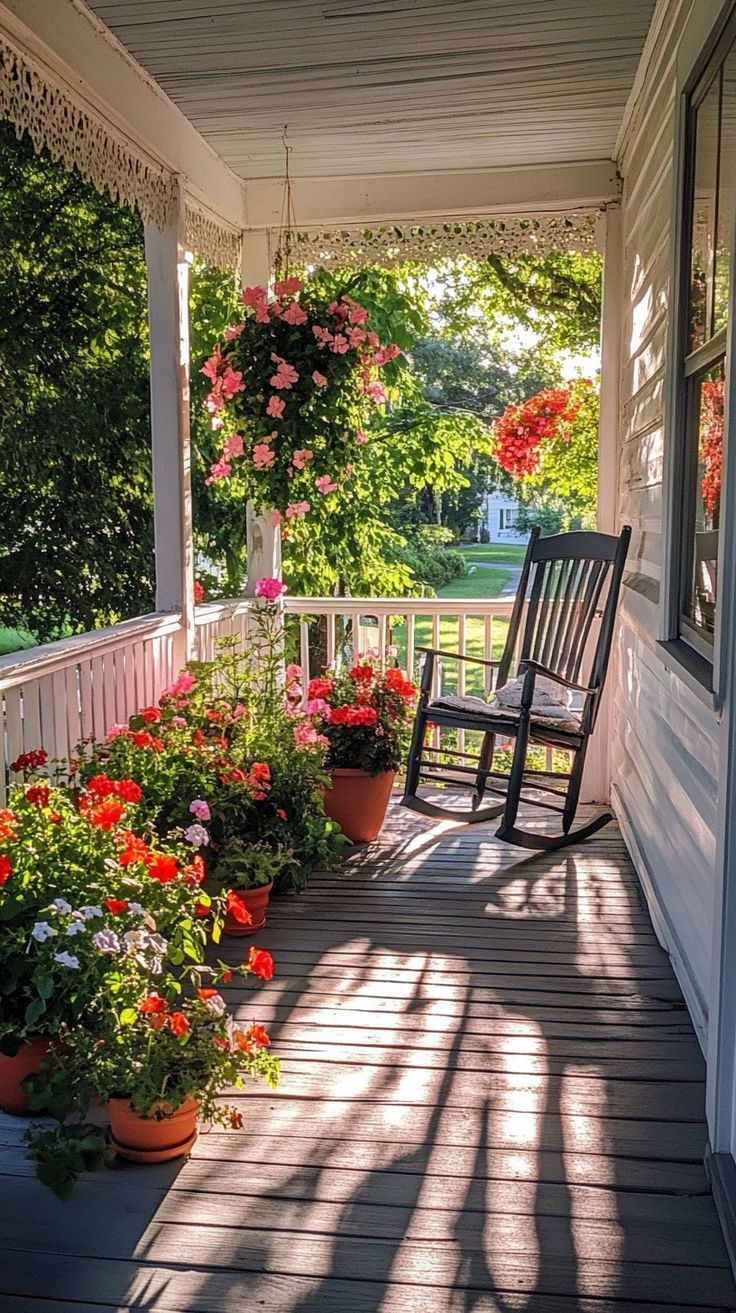 Serene garden porch with potted flowers, rocking chair, and intricate shadows on a sunny day. Porch Oasis, Gray Deck, Grey Deck, Classic Rocking Chair, Tranquil Garden, Serene Garden, Potted Flowers, Garden Porch, Garden Oasis