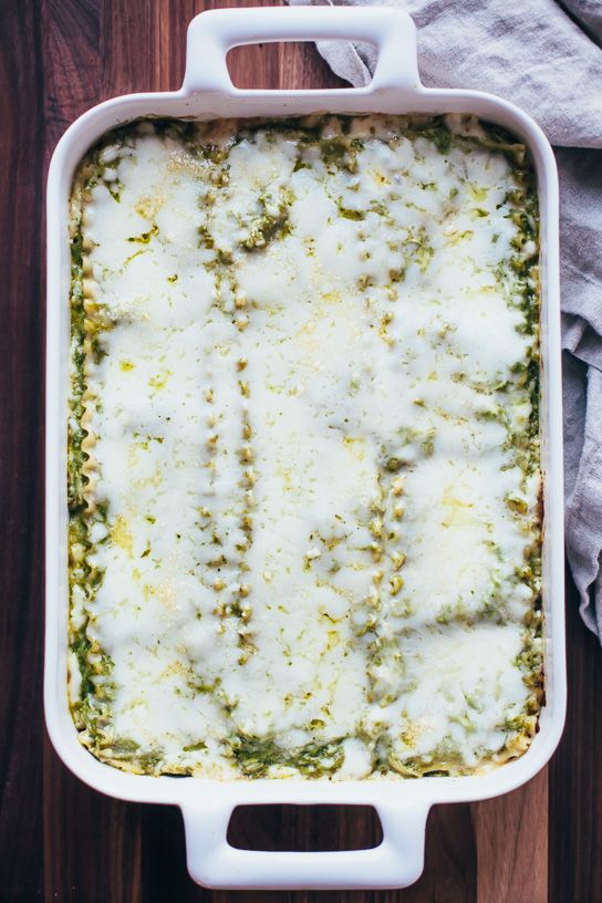 a casserole dish with cheese and spinach in it on a wooden table