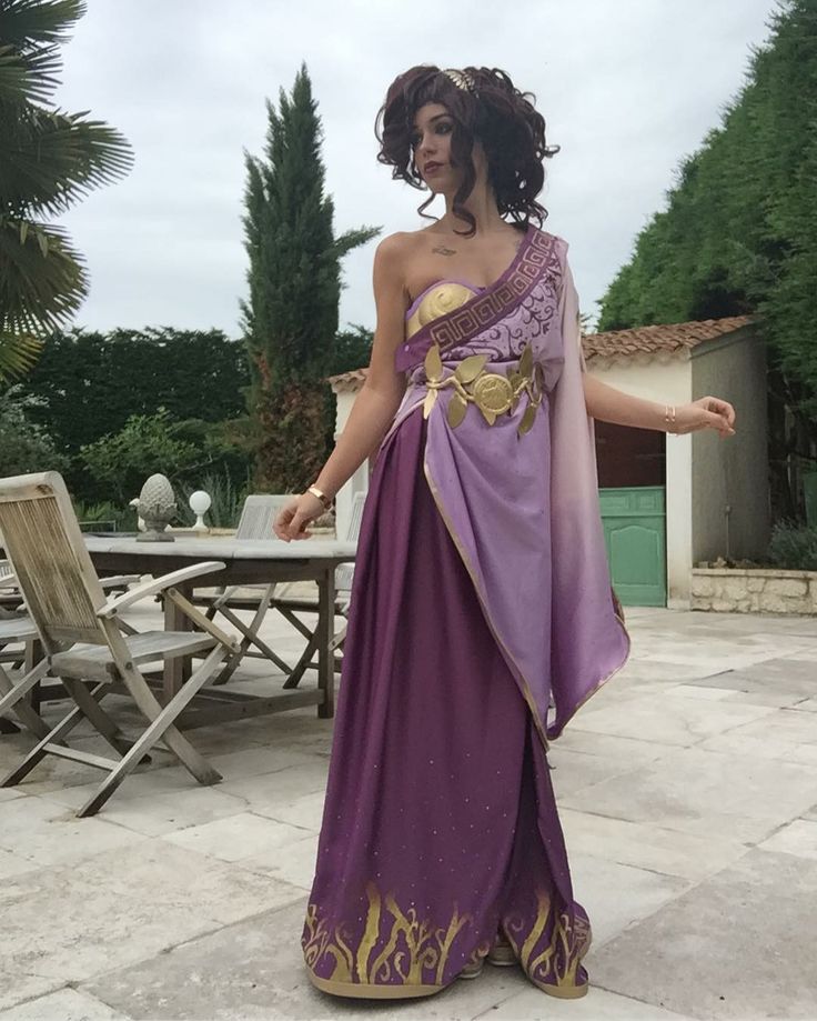 a woman in a purple and gold dress standing on a patio with her arms outstretched