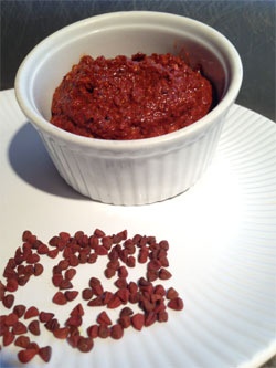 a white plate topped with a bowl filled with red beans next to a pile of raisins