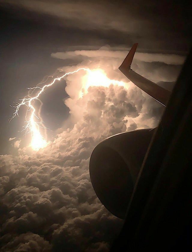 an airplane wing with lightning in the sky