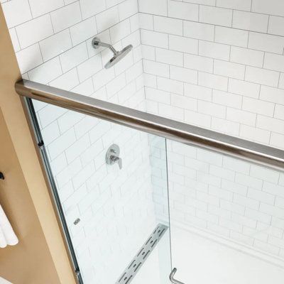 a bathroom with a glass shower door next to a white towel rack and toilet paper