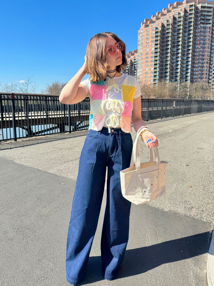 a woman is standing on the street with her hand in her hair and holding a purse