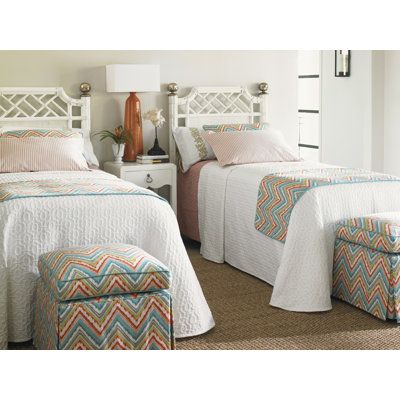 two beds in a bedroom with white headboards and colorful beddings on them