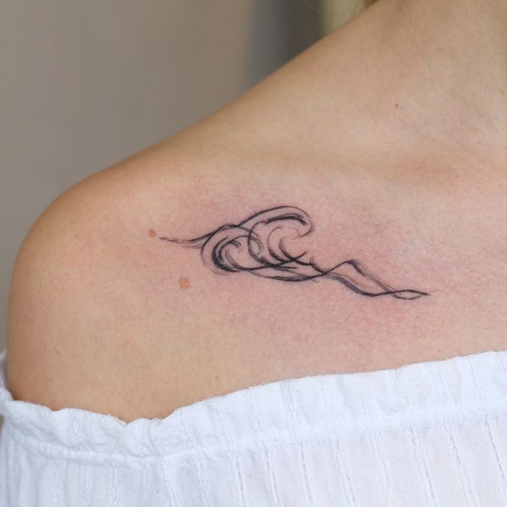 a woman with a wave tattoo on her shoulder