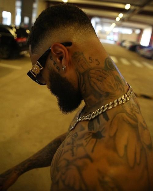 a man with tattoos and piercings on his head wearing a chain around his neck