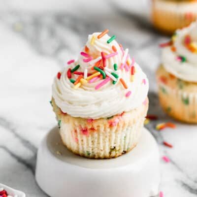 cupcakes with white frosting and sprinkles on a marble surface