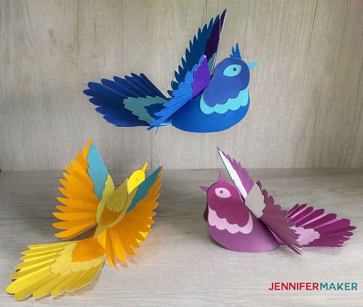 three colorful paper birds sitting next to each other