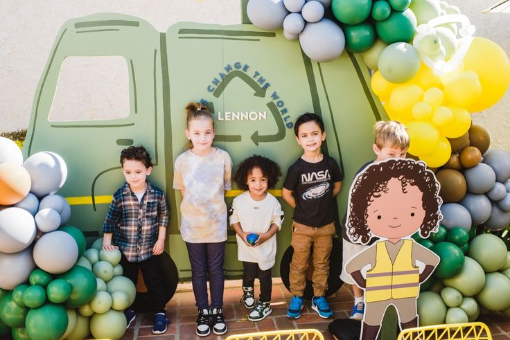 children standing in front of a tent with balloons and paper cutouts on the ground