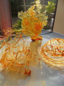 two yellow vases sitting on top of a white table covered in orange string art