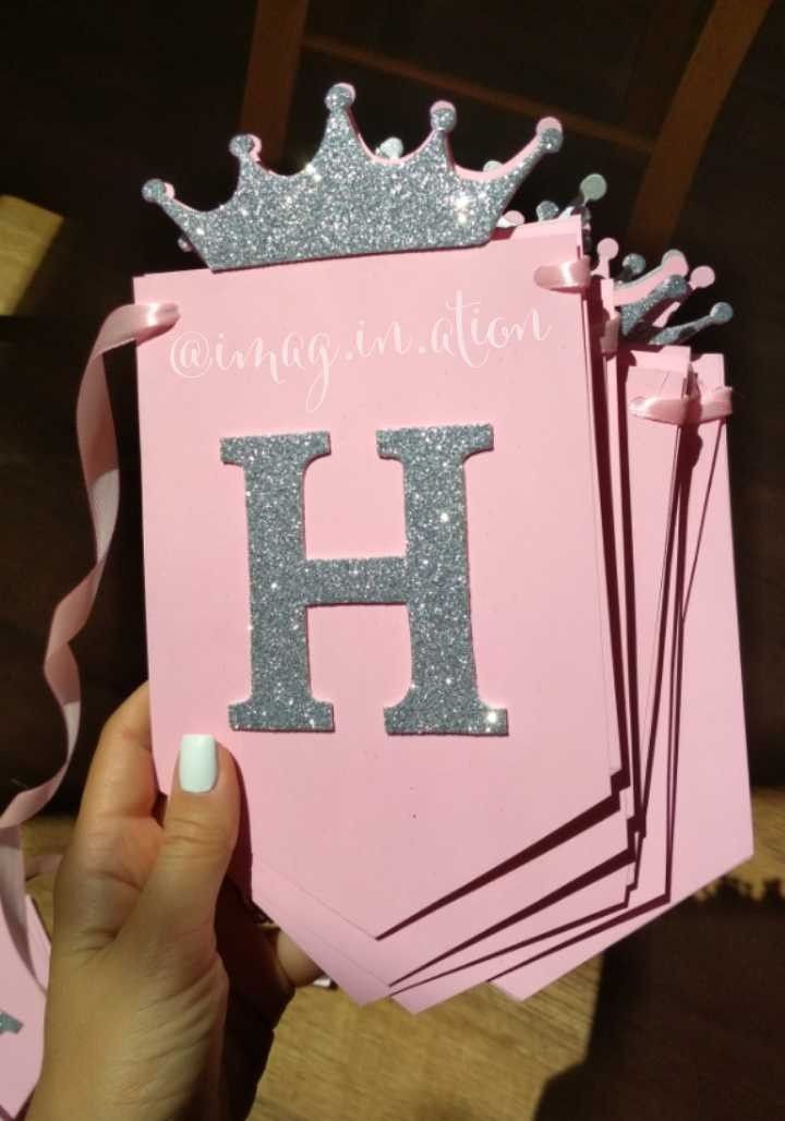 a person holding up a pink card with the letter h on it and a crown on top