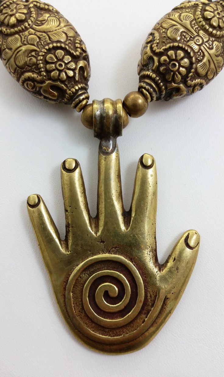 "This gorgeous necklace is comprised of all brass components including a Tibetan brass Hamsa Hand or \"Hand of Fatima\" pendant, Tibetan brass repousse beads and rare brass African pendant beads that are shaped like battle axe heads or crescents. The hamsa hand is a protective amulet, popular throughout Africa, Israel, Turkey and some Middle Eastern countries. The word hamsa means \"five\" and refers to fingers. The hamsa hand is also known as the Hand of Fatima in reference to the daughter of M Bronze Brass Jewelry With Large Beads, Handmade Spiritual Metal Beaded Necklace, Bronze Brass Necklace With Large Beads, Bronze Brass Necklaces With Large Beads, Vintage Bronze Beaded Brass Necklaces, Adjustable Bronze Hand Cast Necklace, Symbolic Gold Beaded Jewelry, Festival Brass Beaded Necklaces, Unique Brass Necklaces With Round Beads