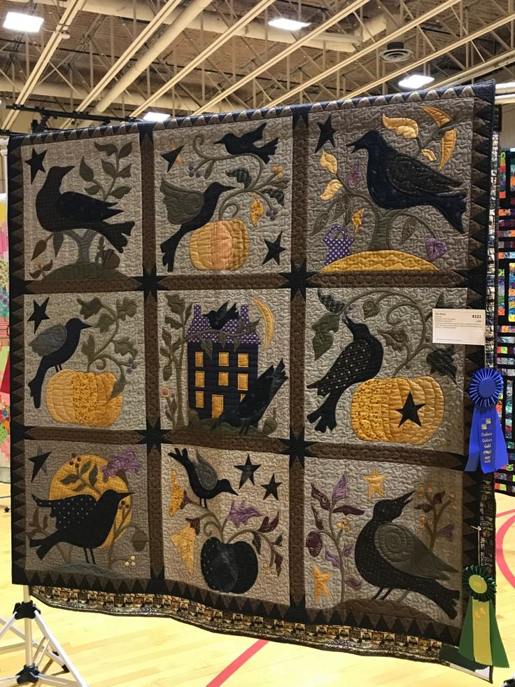 a quilted wall hanging in the middle of a room with lots of decorations on it