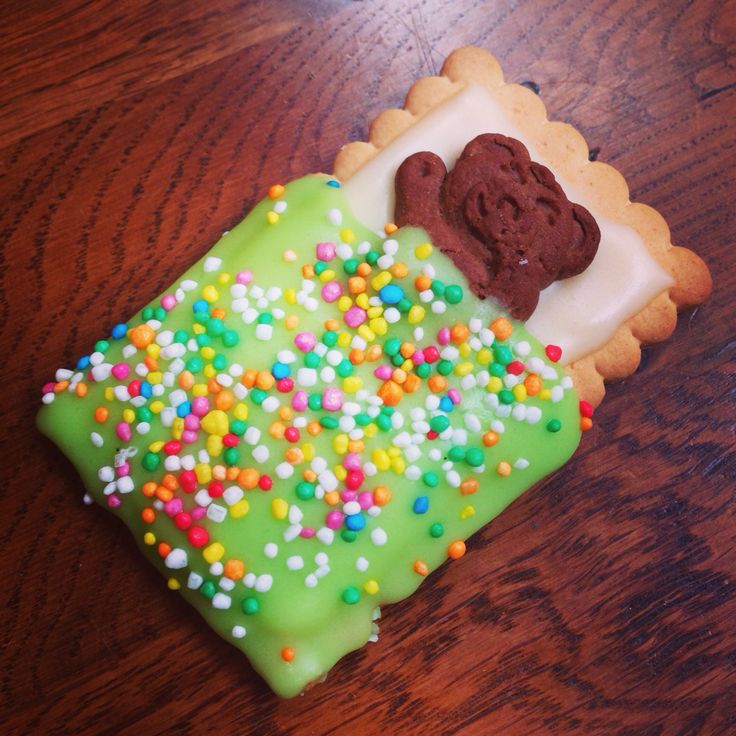 a decorated cookie with sprinkles and cookies on it sitting on a wooden table