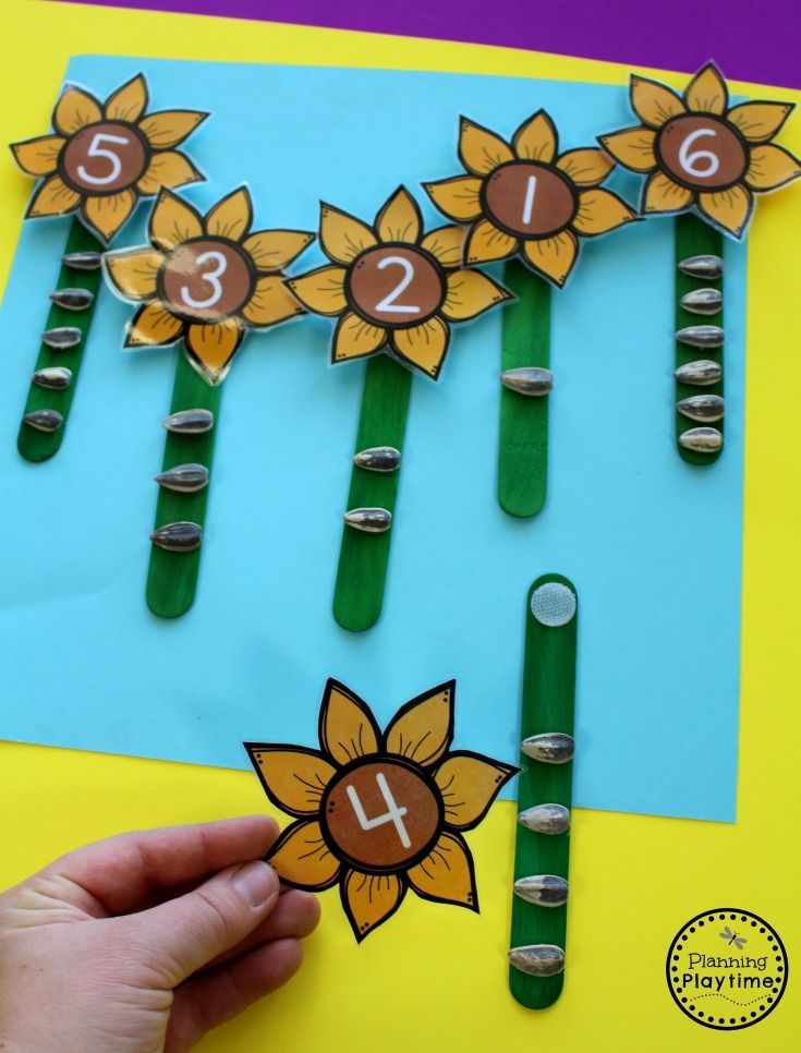 a hand is holding up some flowers made out of popsicles and paper with numbers on them