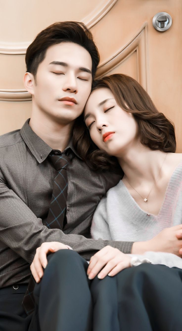 a man and woman sitting next to each other with their eyes closed while they are cuddling