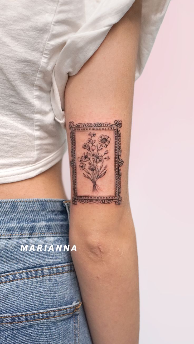 a woman's arm with a tattoo on it that has flowers in the frame