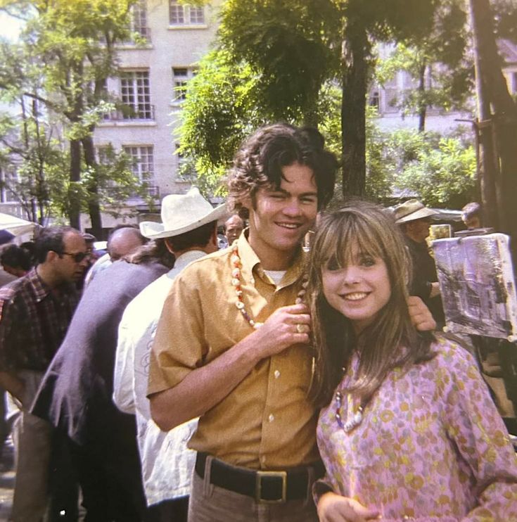 a man and woman standing next to each other in front of a crowd of people