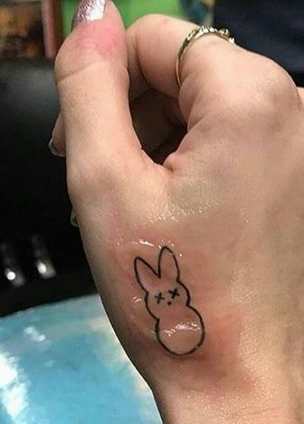 a person's hand with a small tattoo on their left wrist and an outline of a bunny