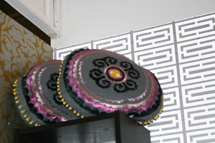 three decorative pillows sitting on top of a shelf