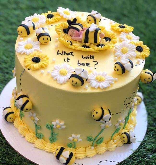 a cake decorated with bees and daisies on top of a green grass covered field