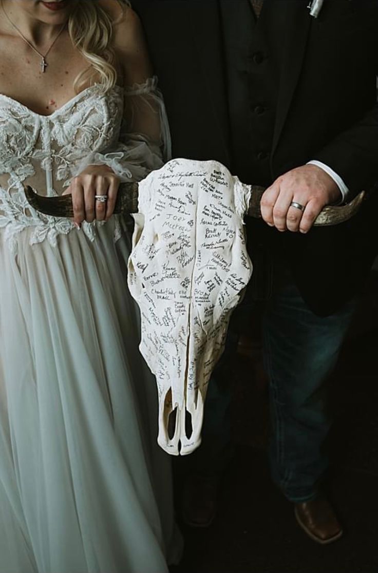 a man and woman holding a fake cow skull with writing on it's side