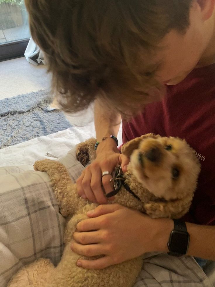 a boy is holding a teddy bear in his lap and touching it with his hand