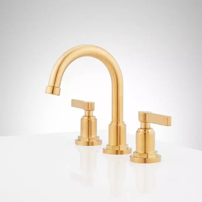 two gold faucets sitting on top of a white counter