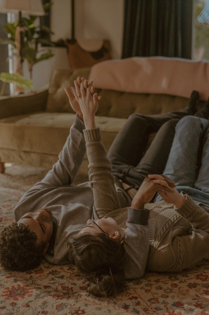 a woman laying on the floor with her hands in the air