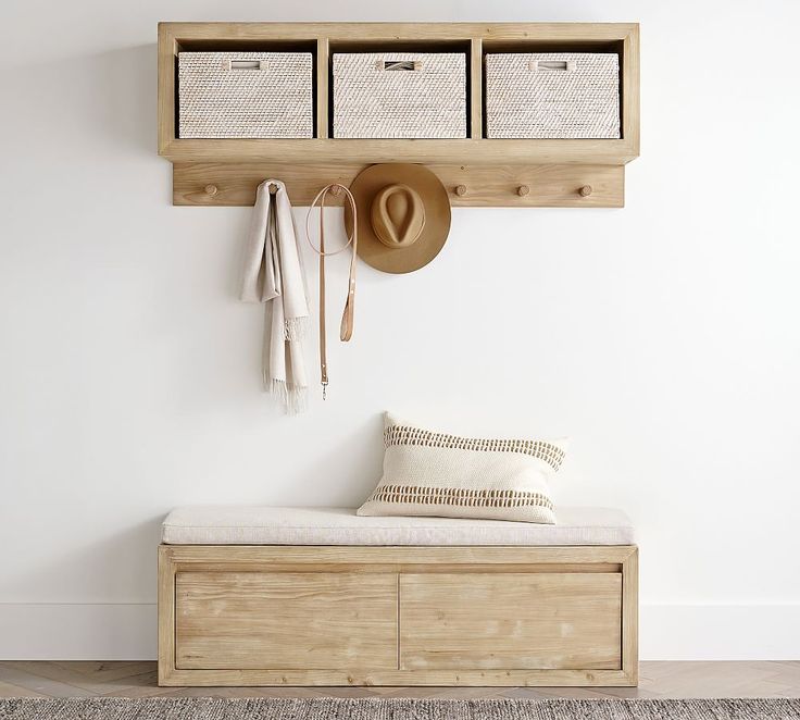 a wooden bench with two baskets and hats on the wall above it, next to a hat rack