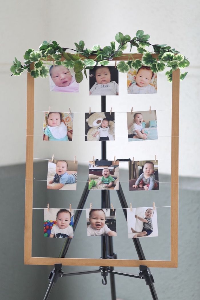 a wooden easel with photos hanging on clothes pegs and greenery around it