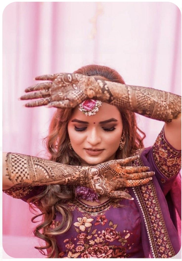 a woman wearing henna and holding her hands up to her head with both hands